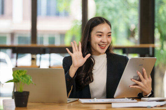An Asian businesswoman videoconferencing with a digital tablet in an office. - Powered by Adobe