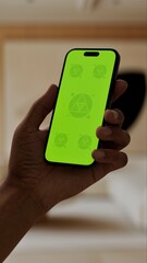 GREEN SCREEN CHROMA KEY A smartphone with a green screen held in a modern urban apartment with large windows and natural daylight illuminating the cozy interior