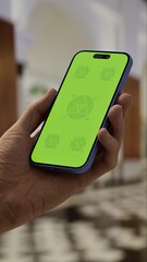 GREEN SCREEN CHROMA KEY Person holding a smartphone in a luxurious lobby with elegant architecture, marble flooring, and blurred background activity