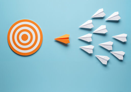 Paper airplanes targeting a goal, symbolizing leadership and strategic direction with a unified approach.