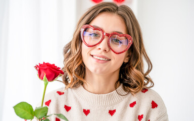 Obraz premium Radiant close-up portrait of a smiling beauty with wavy brown hair, adorned in a cream knit sweater with delicate red hearts