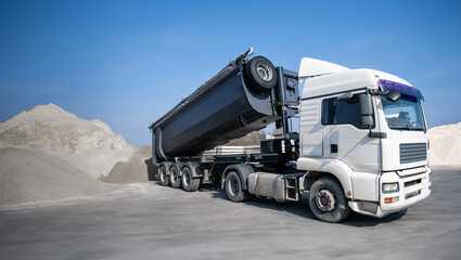 A large dump truck is driving down a dirt road