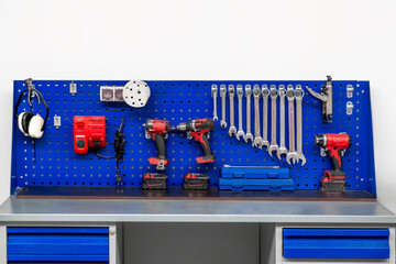 A blue peg board with tools on it
