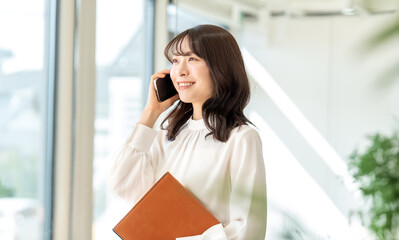 Smiling asian businesswoman talking on phone at office desk