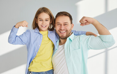 Happy father and preteen son flex their muscles, showcasing their strength and bond. Caucasian man...