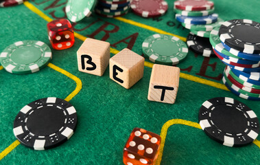 Letters bet and poker chips next to dice 