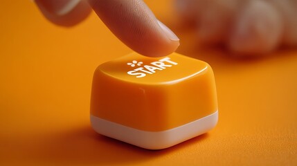 Close-up of a finger pressing an orange 'START' button on a vibrant surface.