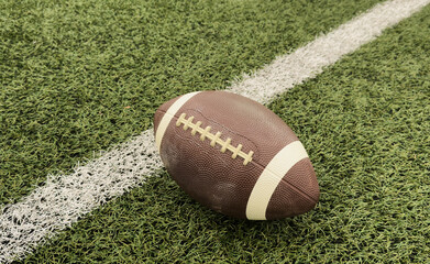 American football ball on green grass field background.