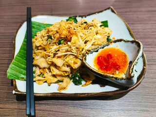 Kwetiaw or Kwetiau, fried with eggs, bean sprouts, vegetables and fried onions. and served with ground chili and chopped chili as a complement.