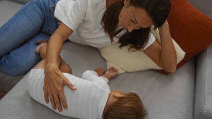 Woman and child relaxing on a sofa in a cozy living room, emphasizing family love and connection in...