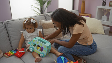 Woman playing with daughter on sofa in cozy living room, showcasing love and family bond through playful interaction with colorful toys in modern apartment setting.