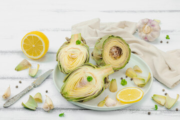 Fresh green artichokes cooking on wooden background. Traditional seasonal ingredients