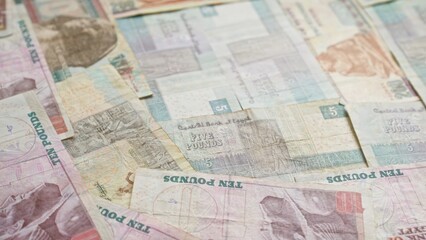 Egyptian banknotes including five and ten pounds scattered, showcasing the currency of egypt in various denominations and designs.