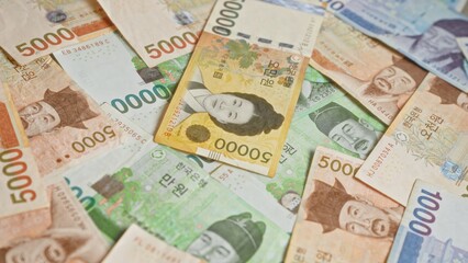 South korean banknotes scattered, featuring colorful won currency notes with historical portraits and complex designs.