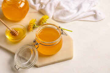Board, jars and bowl with dandelion honey on white background