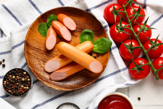 Plate of tasty sausages with basil and tomatoes on table