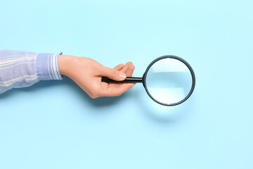 Female hand with magnifier on blue background