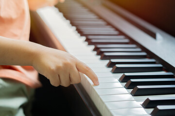 Obraz premium Little boy learning to play the piano at his first time. Close-up of a child's hands playing the piano.
