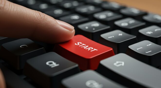 Finger pressing red start key on black keyboard suitable for technology, business, startup concepts. Digital devices, computer accessories.
