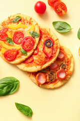 Different tasty mini pizzas on yellow background