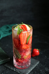 Glass of fresh strawberry mojito on grunge black background
