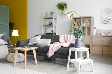 Interior of light living room with glowing lamps and sofa