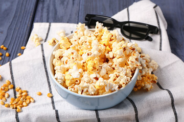 Bowl with tasty popcorn and 3D glasses on blue wooden background