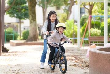 5歳の弟の自転車の練習をサポートする10歳の姉