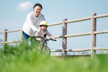 自転車の練習をする5歳の男の子とサポートする父親