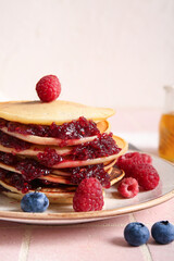 Plate of tasty pancakes with raspberries and blueberries on table