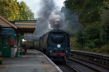 a battle of Britain class pacific locomotive traveling through a southern station in the uk