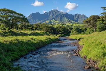 Tranquil stream through lush landscape beneath majestic, jagged mountains