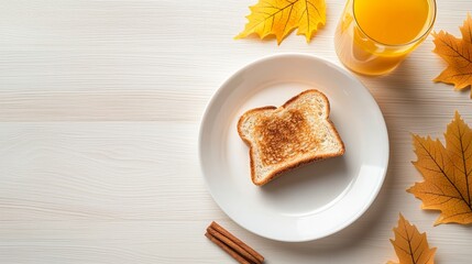 Fototapeta premium Slice of toast is on a white plate next to a glass of orange juice. The toast is toasted and has a browned crust. The plate is placed on a wooden table