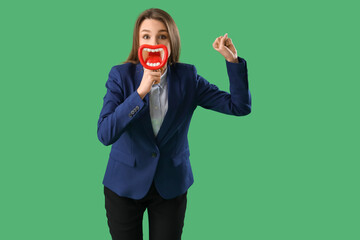 Funny businesswoman with megaphone on green background
