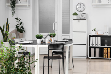 Interior of modern office with workplace, door and plants