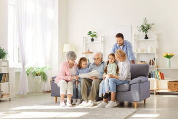 Multi generational extended family reading story together. Grandfather, grandmother, mom, dad and...