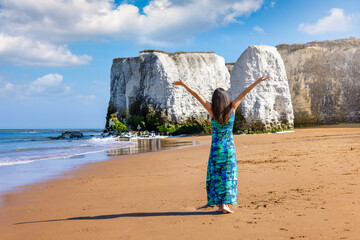 A happy woman enjoys the view of the beautiful beach of Botany Bay in Kent, England, with white cliffs and sunshine