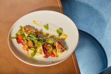 Colorful plate of contemporary cuisine featuring fresh vegetables and herbs in a stylish dining setting