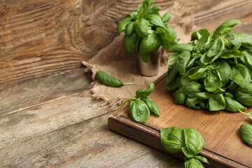 Board with fresh green basil leaves on wooden background
