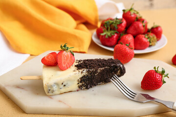 Board with tasty cheesecake pop and strawberry on table
