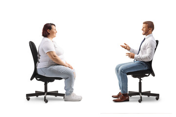 Professional man sitting in an office chair and talking to a corpulent casual woman
