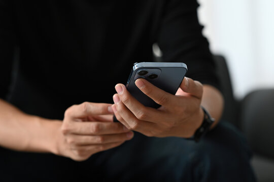 Close-up view of a man holding and using a smartphone. Focus on hands and mobile device, representing modern technology, communication, and digital lifestyle