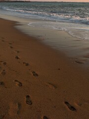 Foot steps on sand with sea shore at beach close up. Summer vacation season. 
