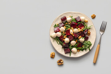 Plate of fresh salad with beet and mozzarella cheese on grey background
