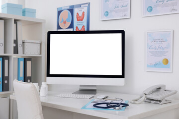Clipboard, pen, computer, telephone and stethoscope on desk in doctor's office