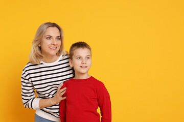 Happy mother and son on orange background. Space for text