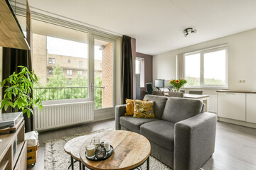 A bright and airy modern living room featuring a comfortable sofa, wooden coffee table, and a view...