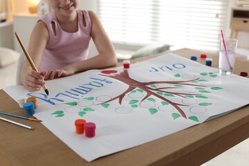 Girl drawing her family tree with paints at wooden table indoors, closeup