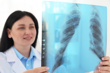 Smiling doctor examining lung MRI scan in clinic, selective focus