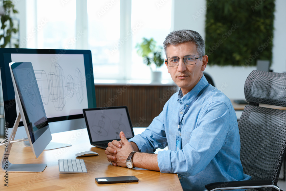 Poster portrait of engineer at table with devices in office